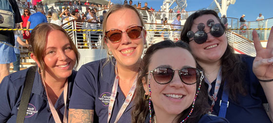Four team members in navy shirts pose for a selfie at Magic Kingdom