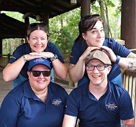 Four team members smile together inside a covered outdoor vehicleFour team members smile together inside a covered outdoor vehicle